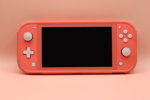 Close-up of a pink digital gaming console with buttons and screen on a neutral background.