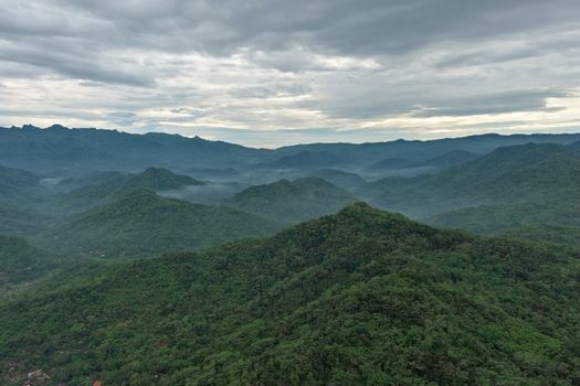A scenic landscape of lush green mountains and mist in Kecamatan Purworejo, Indonesia.