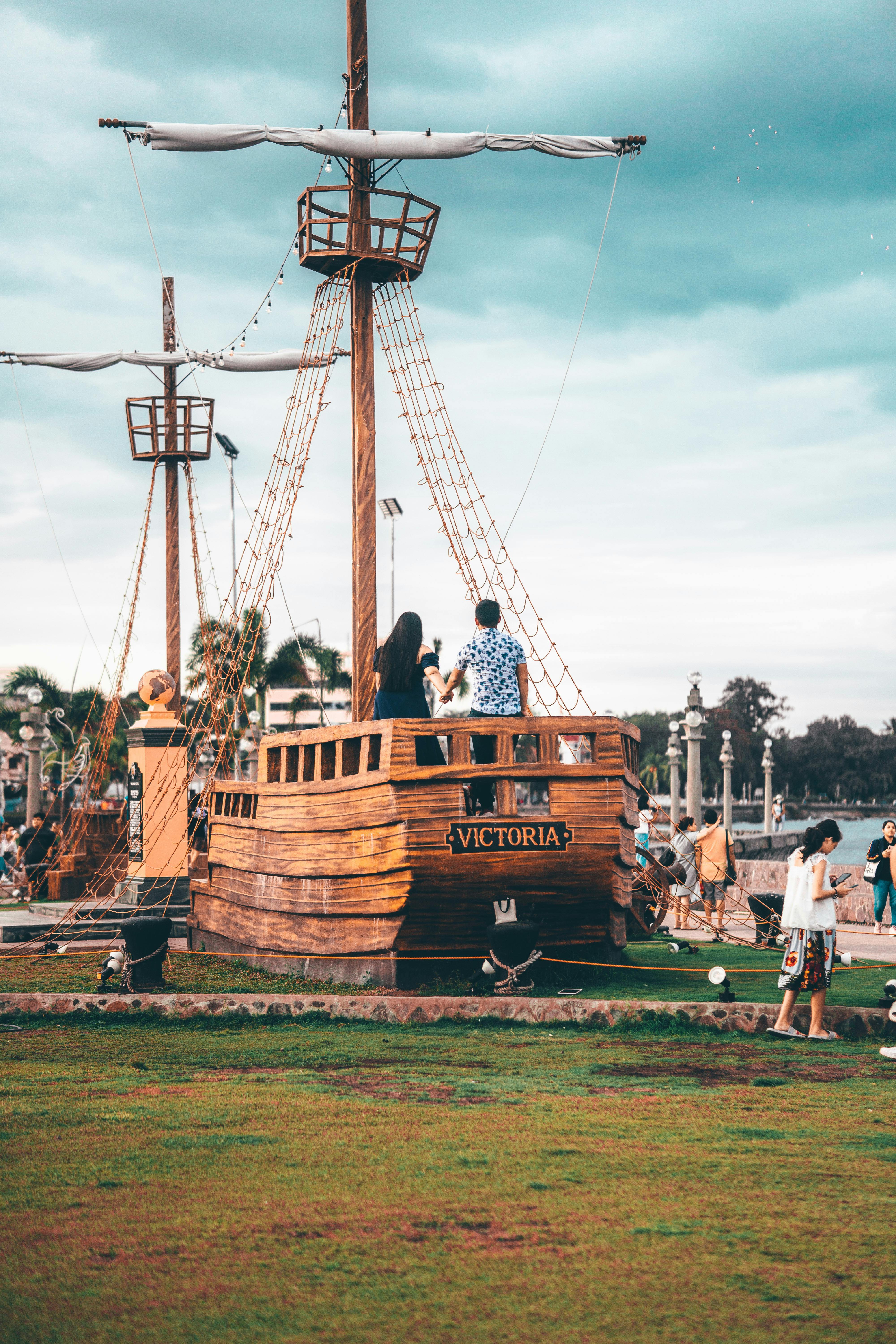 couple holding hands on a small replica of a sailing ship