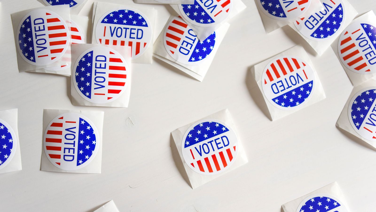 Top view set of small round stickers with flag of United Stated and I voted text scattered on white surface