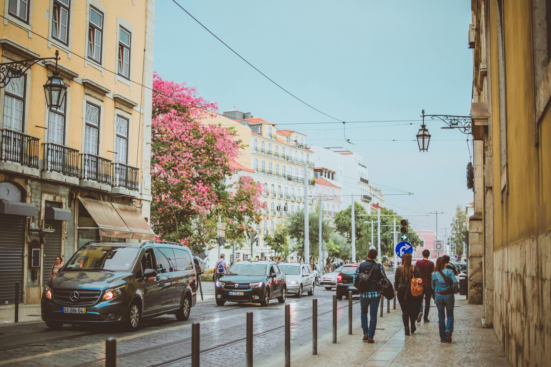 Vibrant Lisbon street with pedestrians and vehicles under a clear sky.