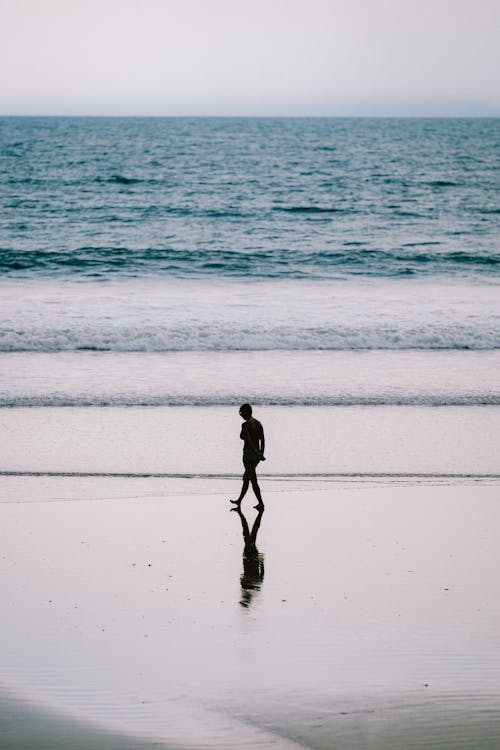 Silhouette of Woman Walking on Beach