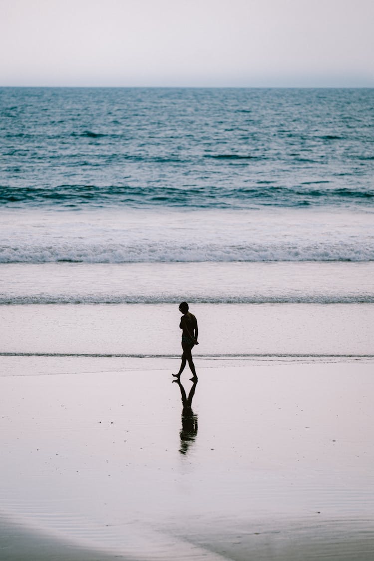 Silhouette Of Woman Walking On Beach