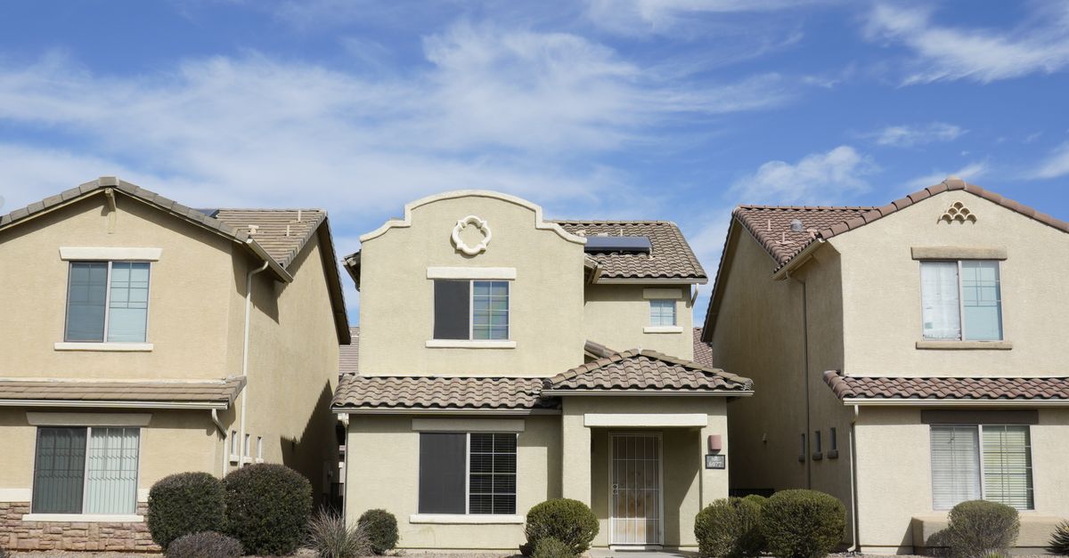 Three adjacent houses in a suburban neighborhood of Tucson, Arizona under a clear sky.