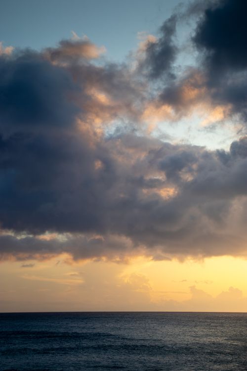 Free A stunning sunset over the ocean with dramatic clouds and a peaceful seascape. Stock Photo