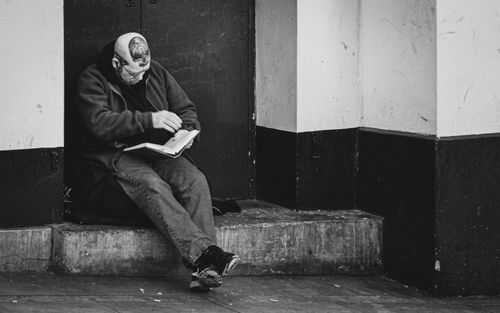 Free A man with tattoos sitting on a step, reading in London. Stock Photo