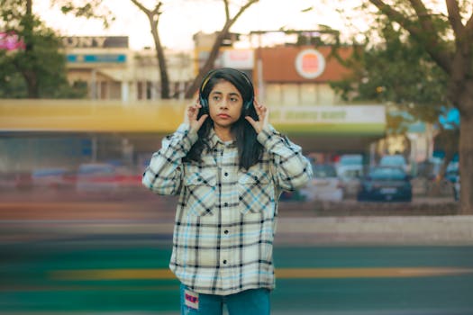A teenage girl with headphones standing outdoors in an urban environment with motion blur in the background.
