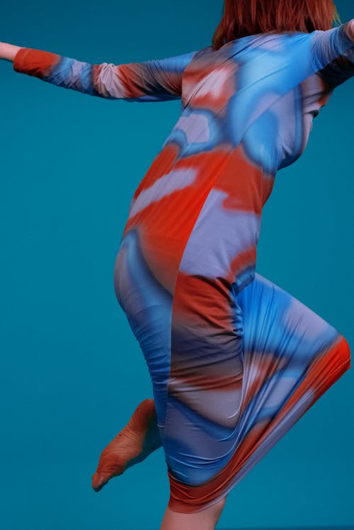 Woman in Colorful Dress Dancing on Blue Backg