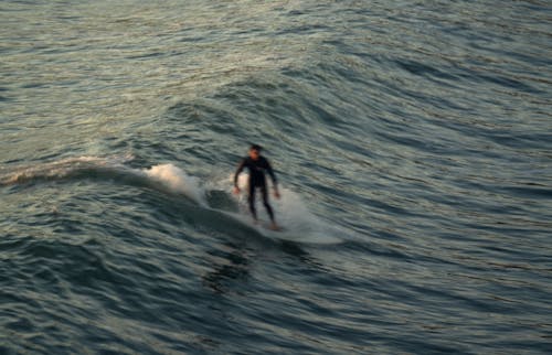 Blurry Photo of Man Surfing on Wave