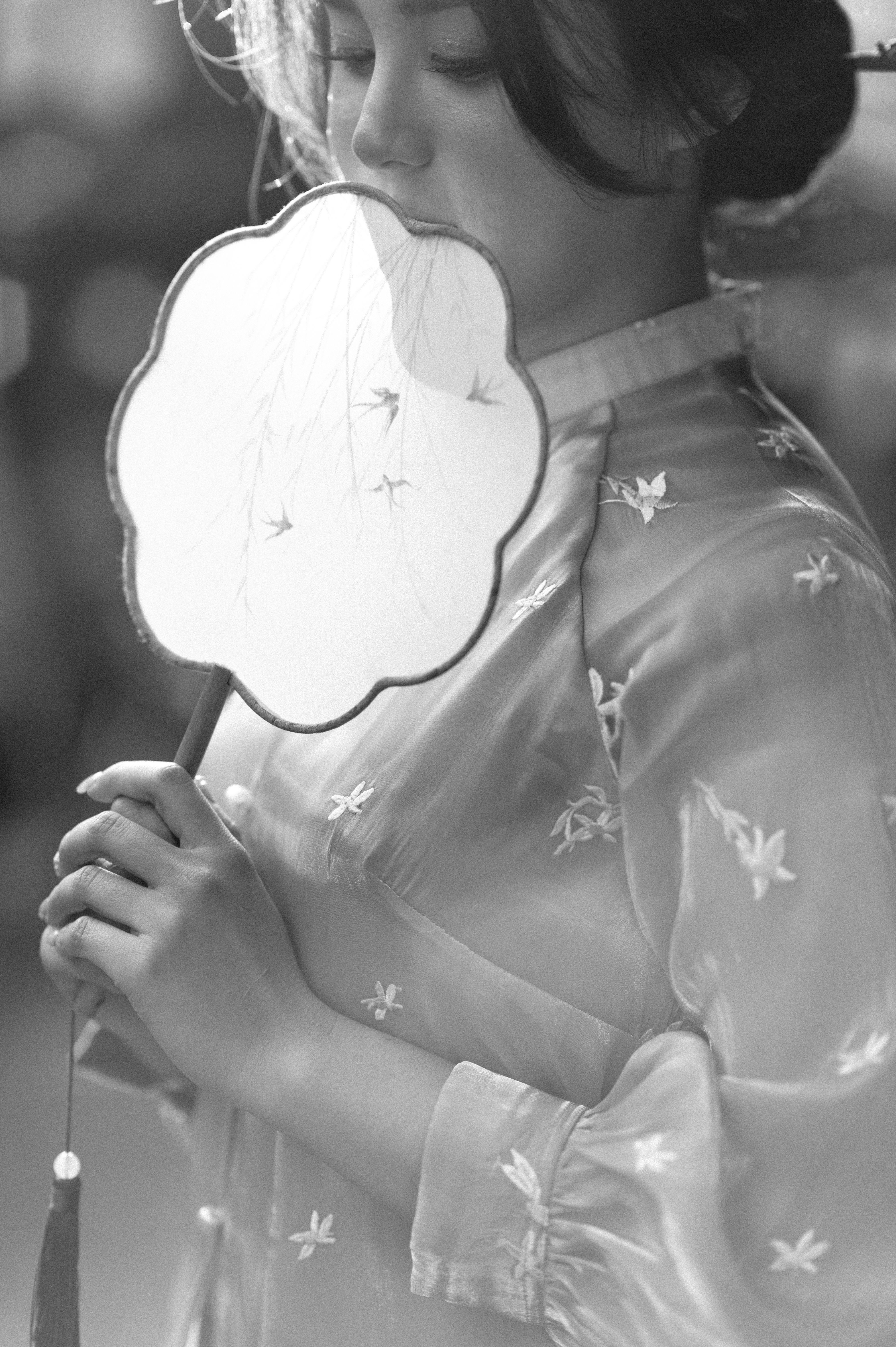 Black and white portrait of a woman in Lạng Sơn, Việt Nam, holding a traditional hand fan.