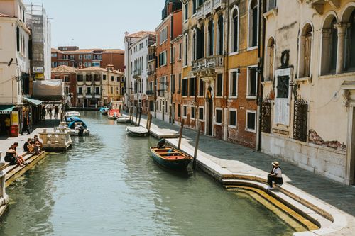 Free Charming Venetian canal scene with gondolas, historic buildings, and people enjoying the sunny day. Stock Photo