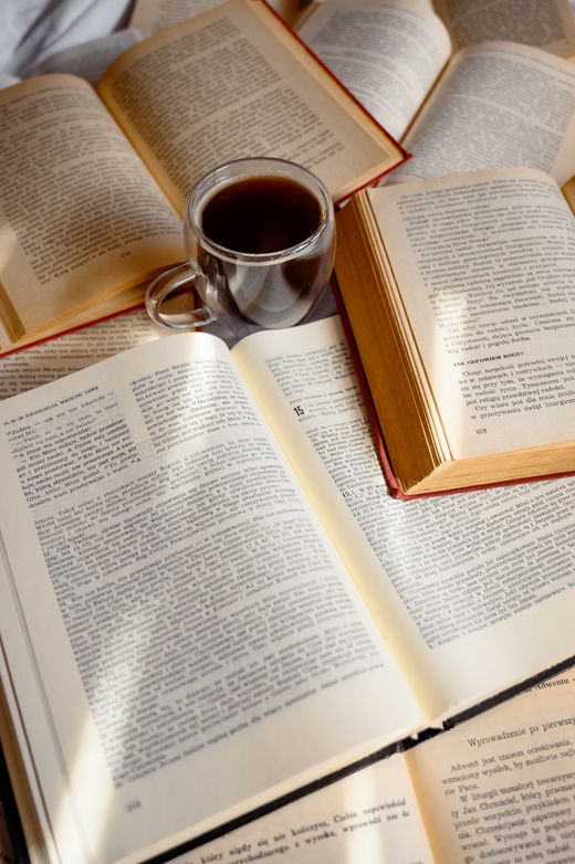 Open books and a cup of coffee on a warm-lit table — Meri Verbina on Pexels