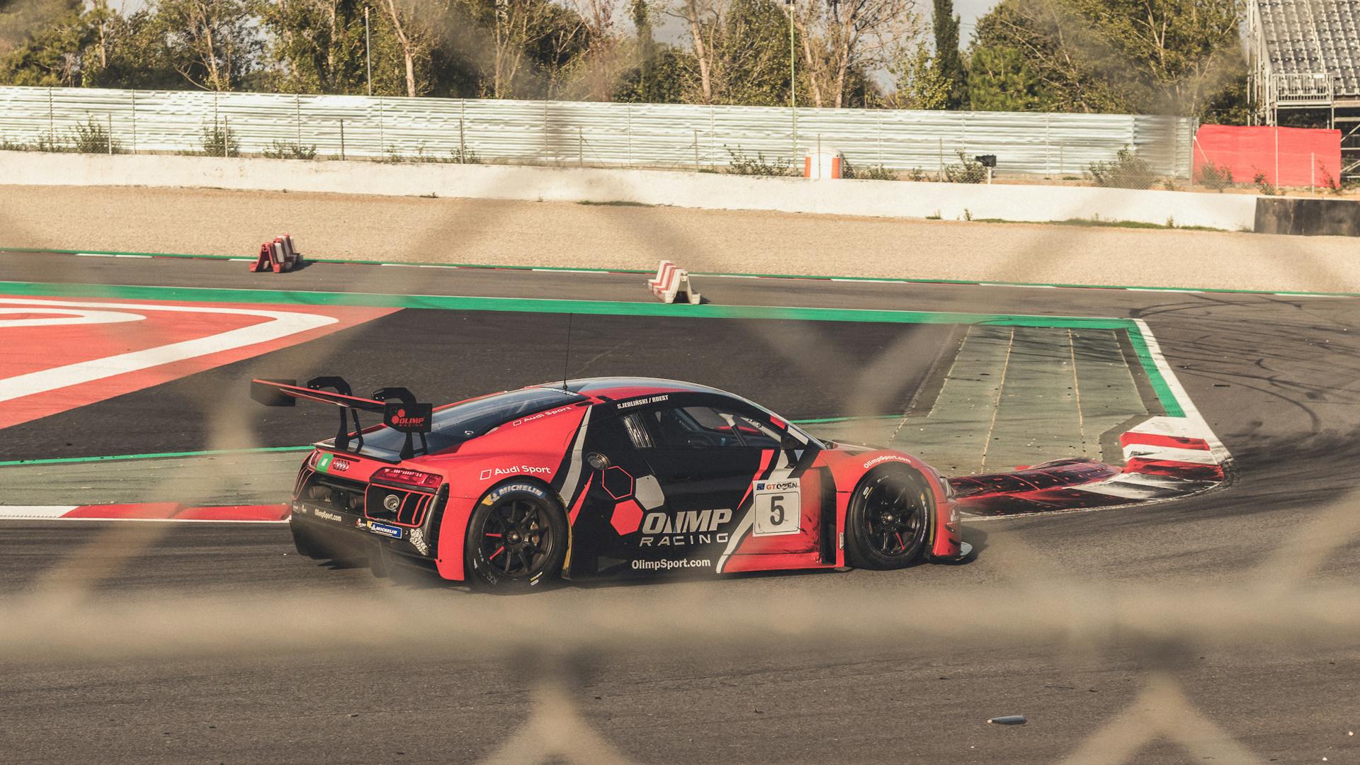 Close-up of a red sports car racing on an outdoor track, capturing speed and excitement.