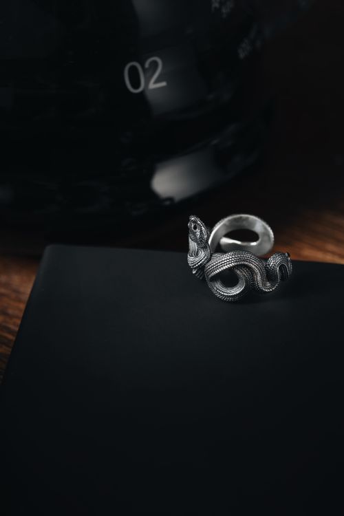 Free A luxurious silver snake-shaped ring displayed on a black surface, showcasing elegance and style. Stock Photo