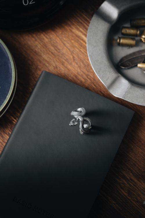 Free Close-up of an elegant silver knot ring on a black notebook, styled in a still life arrangement. Stock Photo