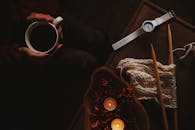 温暖的平地上，咖啡、手表、编织针和蜡烛构成了一幅场景，非常适合室内舒适的时刻