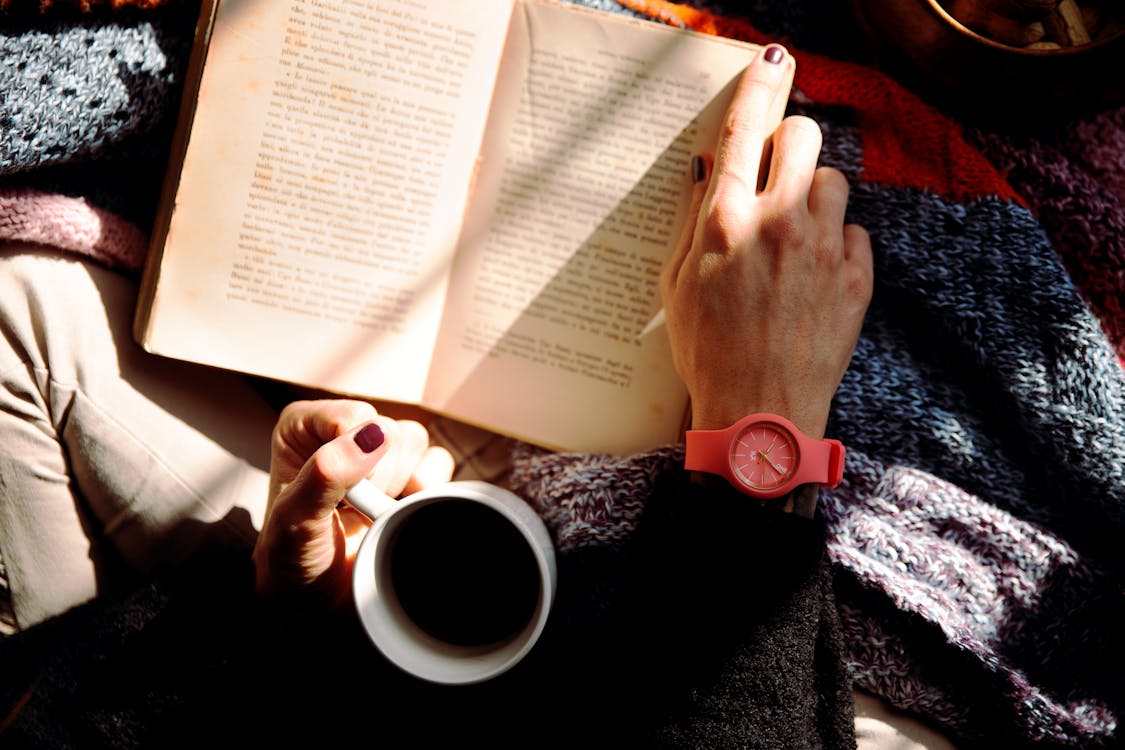 Free Person Reading Book and Holding Coffee Stock Photo