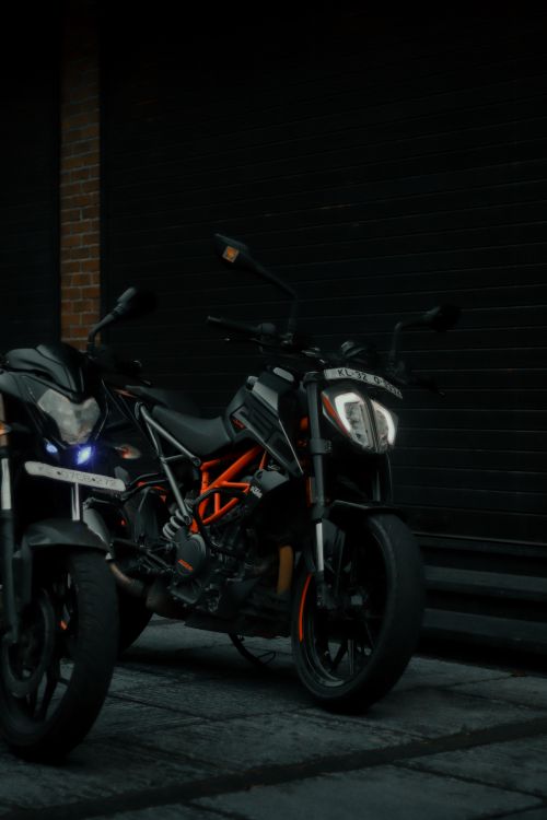 Free Two modern motorcycles parked on a city street at night, showcasing urban style and transportation. Stock Photo