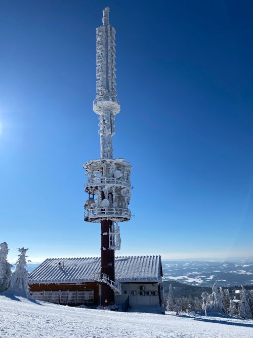 Free A snow-covered communications tower stands in a winter wonderland against a clear blue sky. Stock Photo