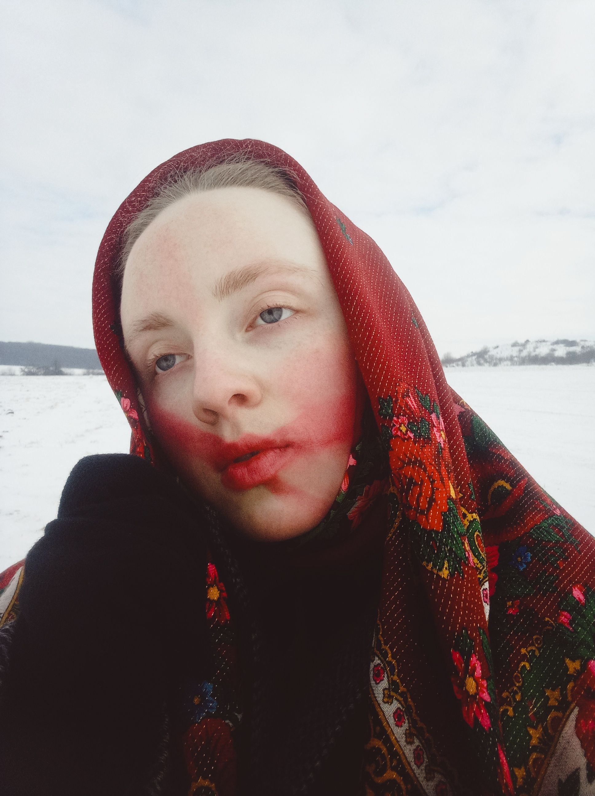Woman with headscarf in snowy landscape, expressing contemplation.