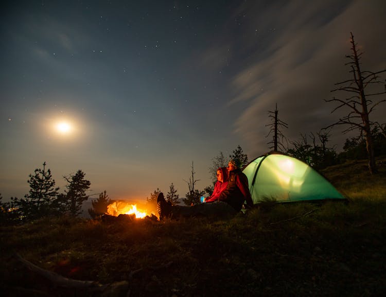 A Couple Camping By Fire Under Moon Light