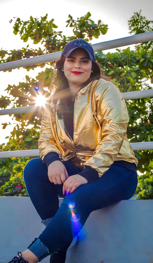 Young Woman in Casual Clothing Sitting Outdoors and Smiling 