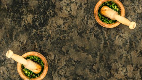 Aerial view of wooden mortars and pestles filled with fresh green pesto.