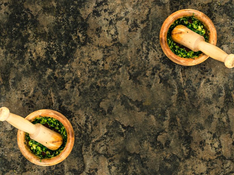 Aerial view of wooden mortars and pestles filled with fresh green pesto.