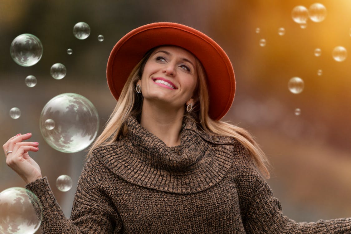 Smiling Woman Wearing Brown Sweater Surrounded by Bubbles