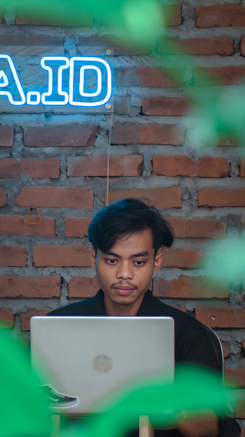 Young Man Sitting and Using a Laptop 