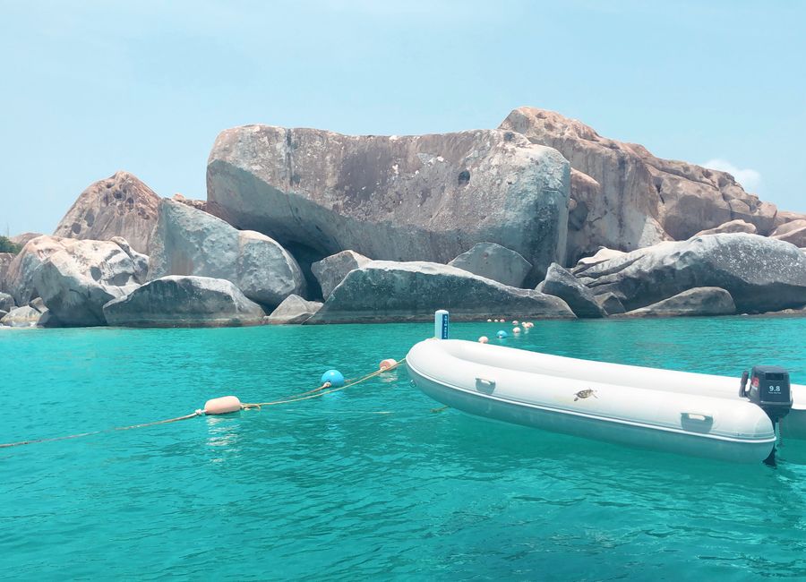 A tranquil scene featuring a boat and rocky shoreline at The Baths, British Virgin Islands.