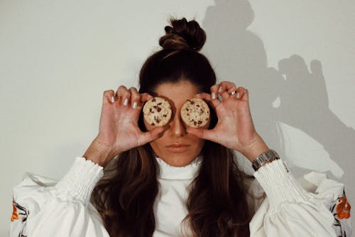 Woman Covering Eyes With Two Chocolate Chip Cookies