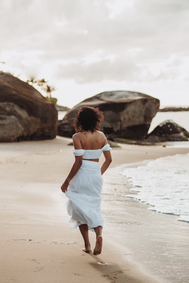 Back View Of Woman Walking On The Beach 