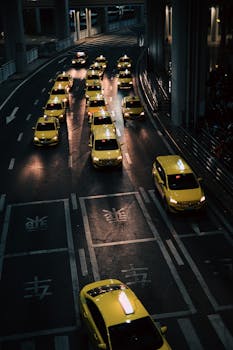 High angle view of lined yellow taxis on urban street during nighttime.