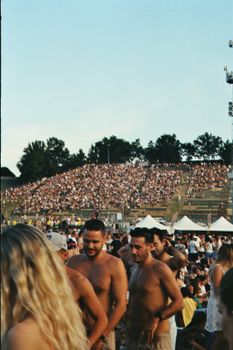 Energetic outdoor concert scene with a massive crowd enjoying the event during a sunny day.