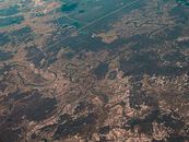 Aerial shot capturing the intricate patterns of a meandering river and surrounding landscape.