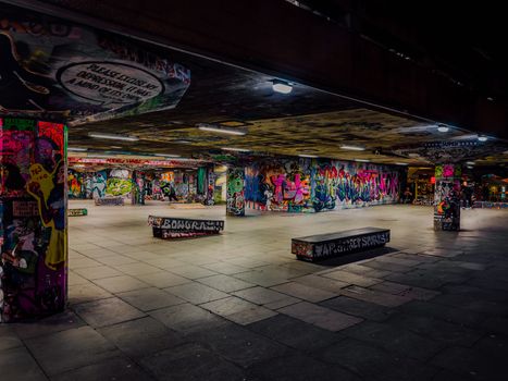 Colorful graffiti-covered skatepark in London, showcasing urban art under night lights.