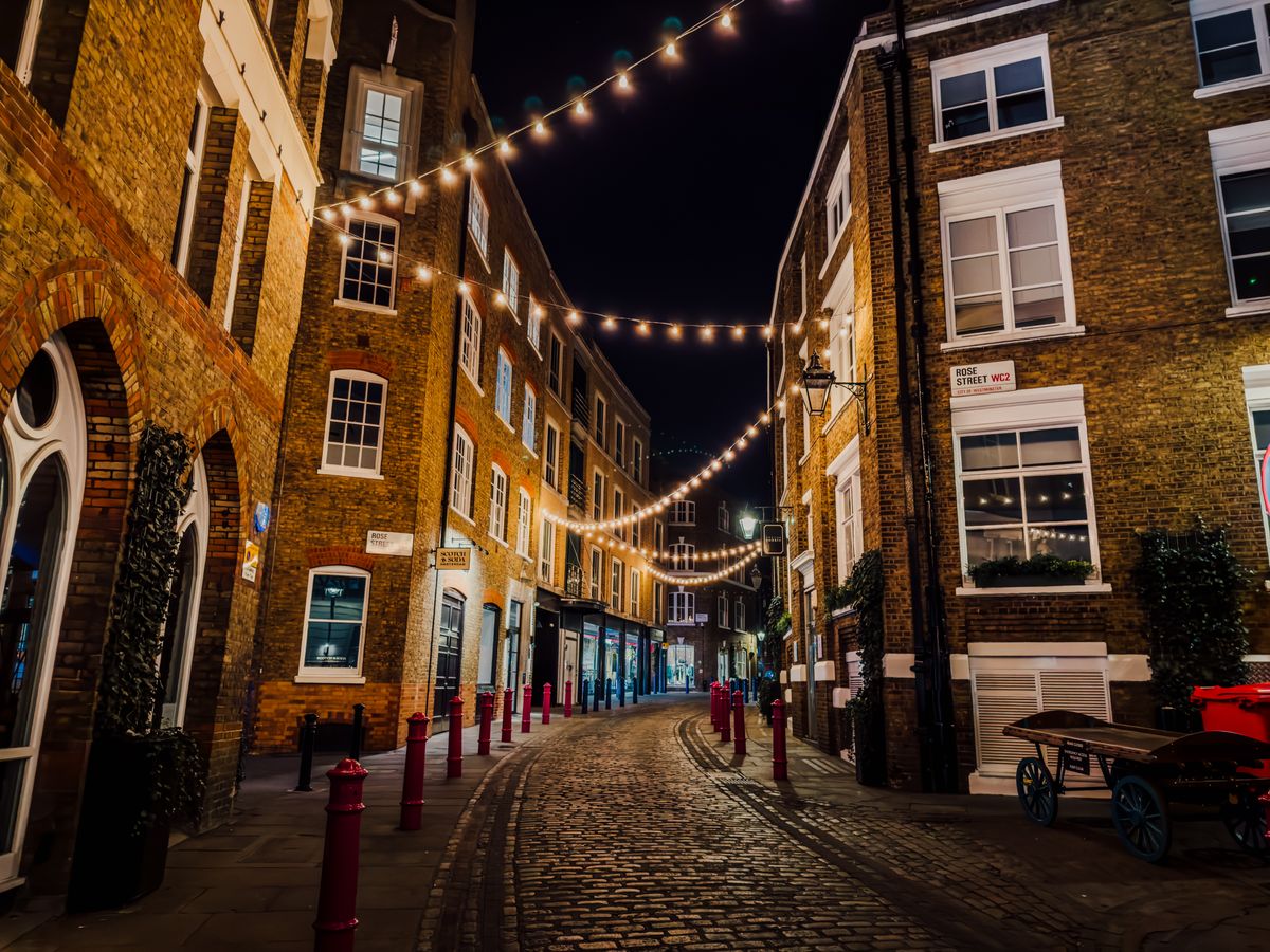 String lights above a cobblestone street in Soho. Atmospheric photographic reference.
