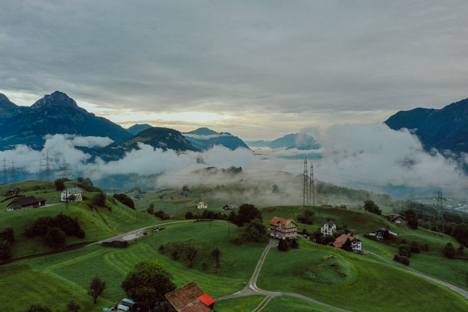 Breathtaking aerial view of Swiss villages nestled in the Alps surrounded by fog and lush greenery.