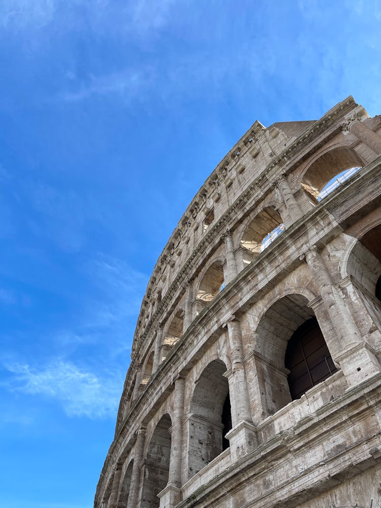 Low Angle Shot Of The Colosseum Under Blue Sky In Rome, Italy 