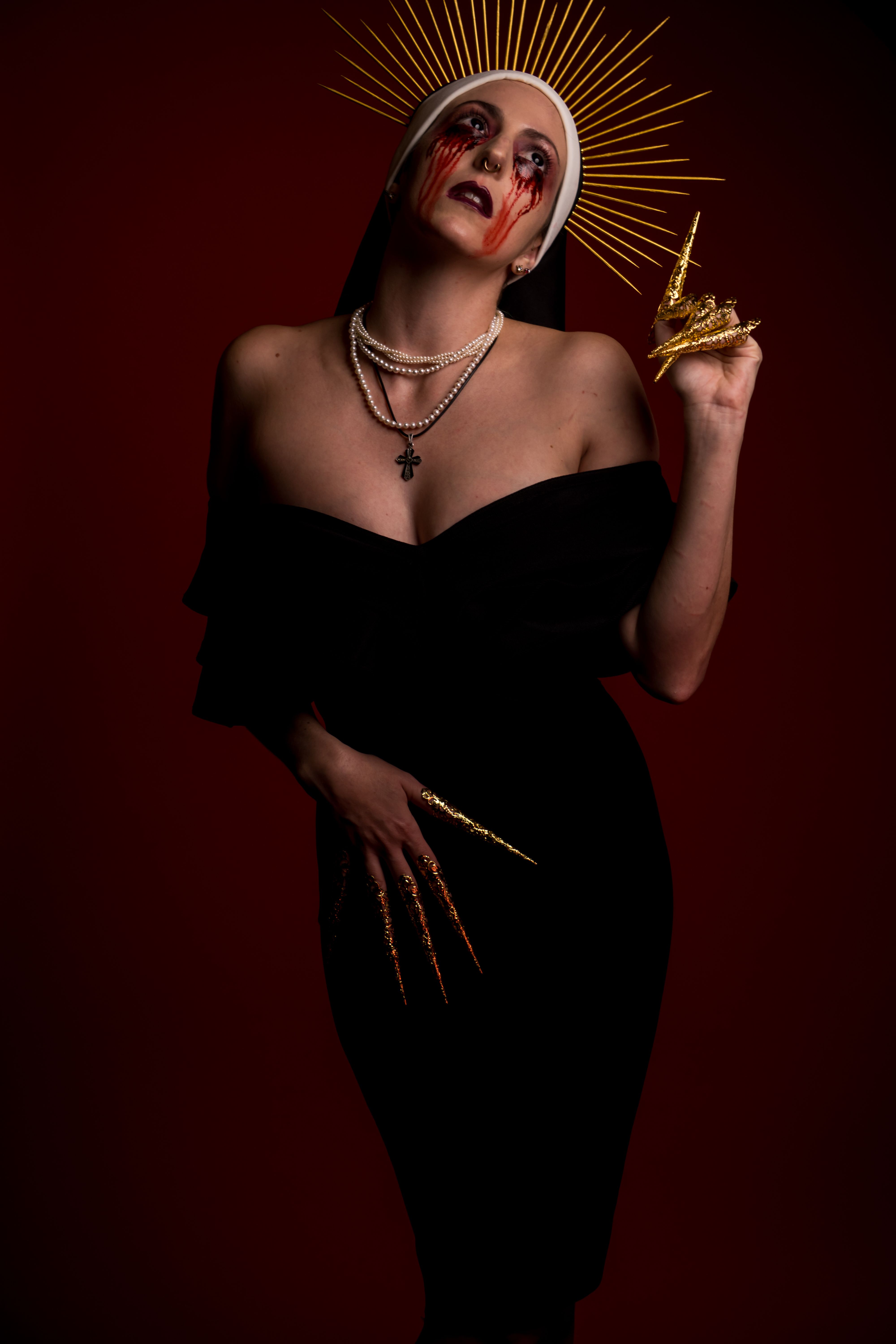 Elegant dark fantasy portrait of a woman with dramatic makeup and accessories in a studio setting.