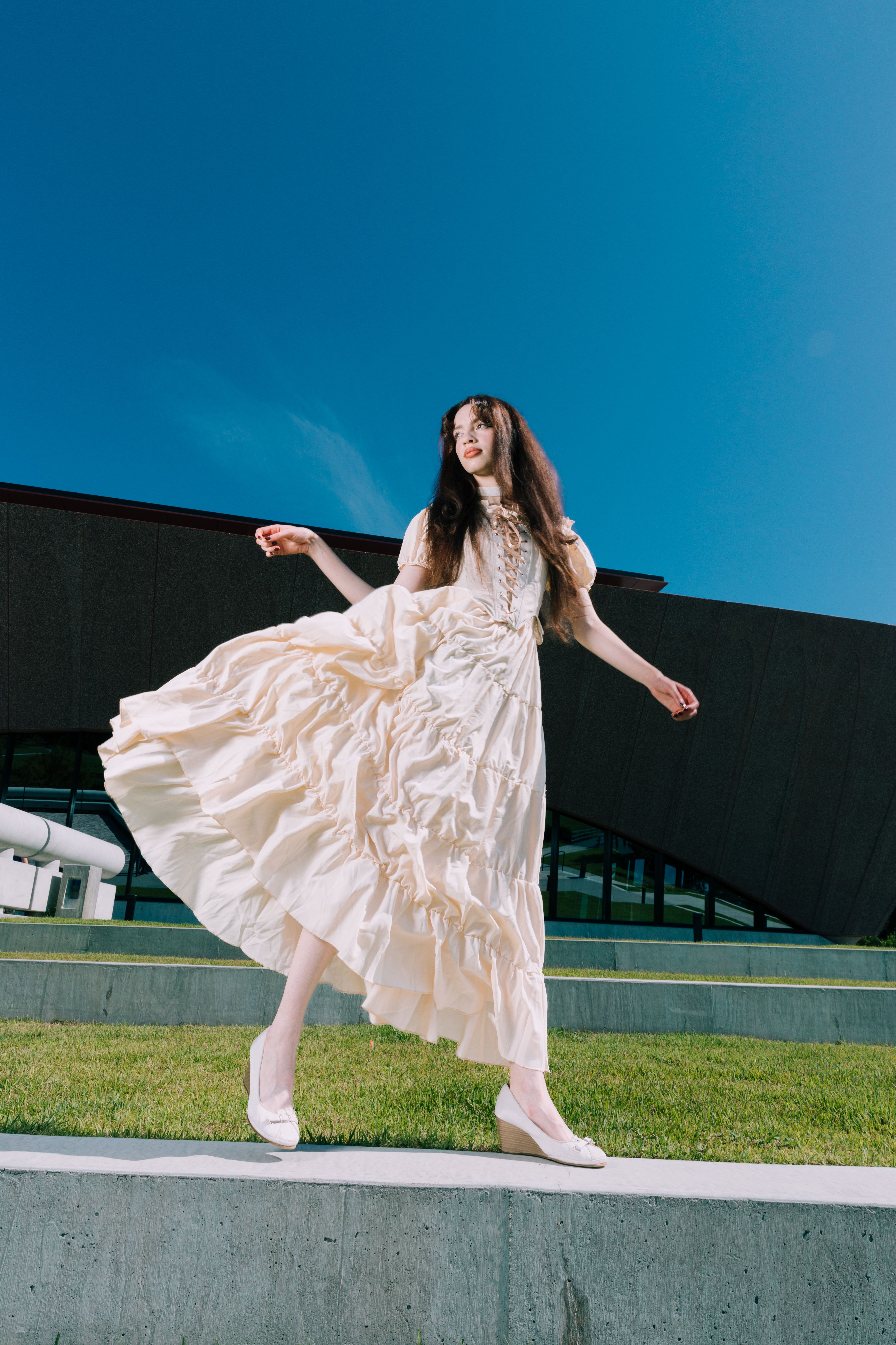 Stylish woman in a white dress posing elegantly against a modern building in Orlando.