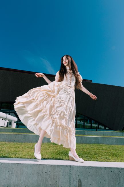 Stylish woman in a white dress posing elegantly against a modern building in Orlando.