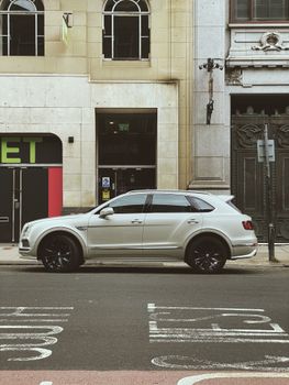 A luxury white SUV parked on a historic street in Glasgow, Scotland.