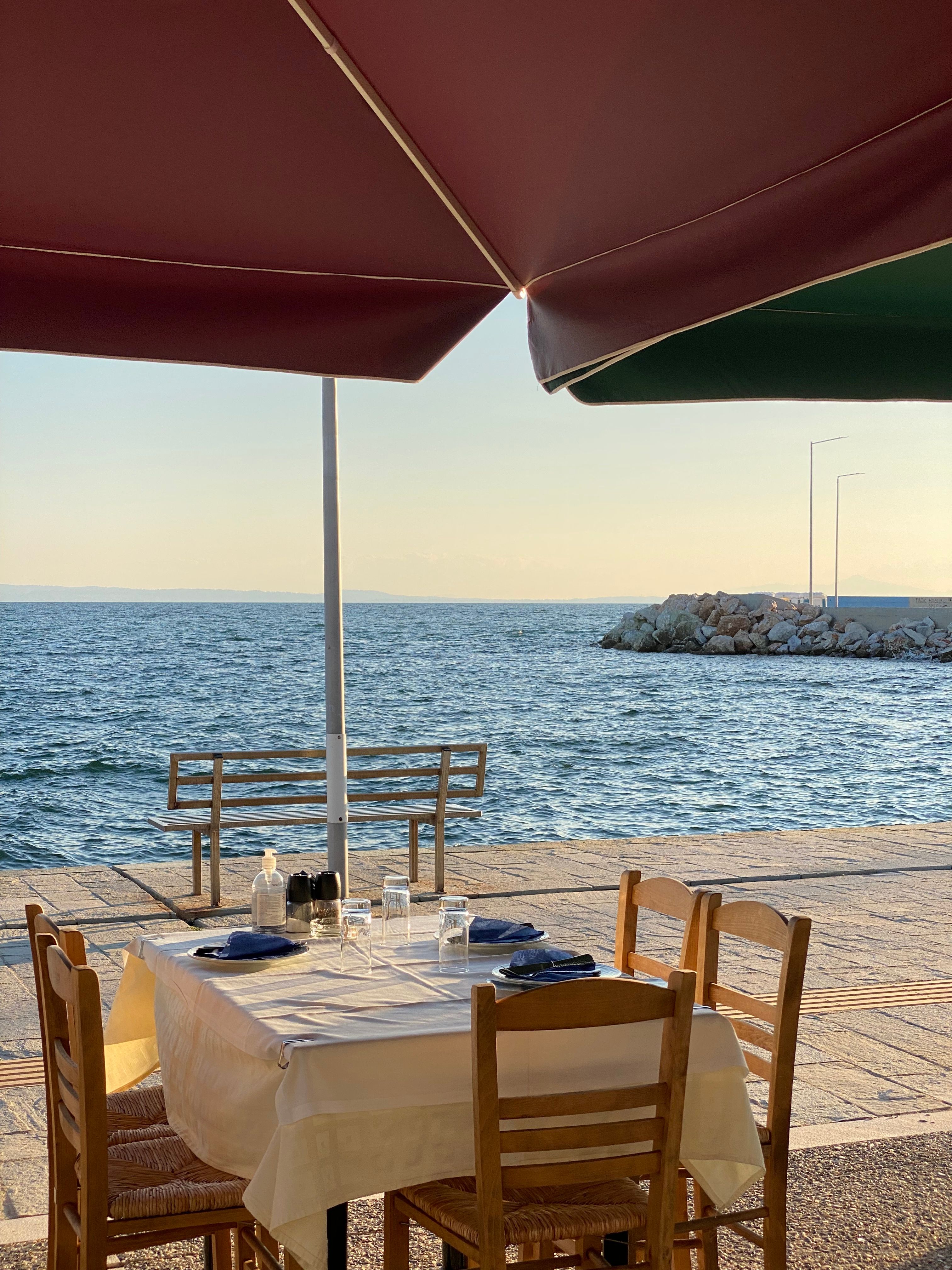 Enjoy a serene seaside meal in Thasos, Greece, with a scenic ocean view and summer breeze.