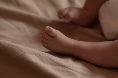 Free Close-up of a newborn baby's foot resting on a soft beige blanket, symbolizing innocence and purity. Stock Photo