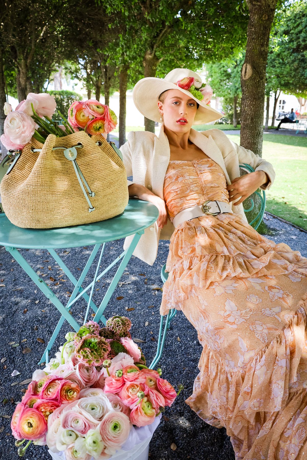 A woman in a floral dress sitting on a chair in a park — garden party style