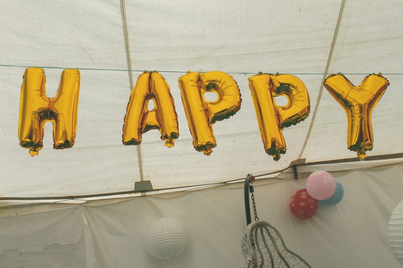 Gold balloons hanging on strings against a wall