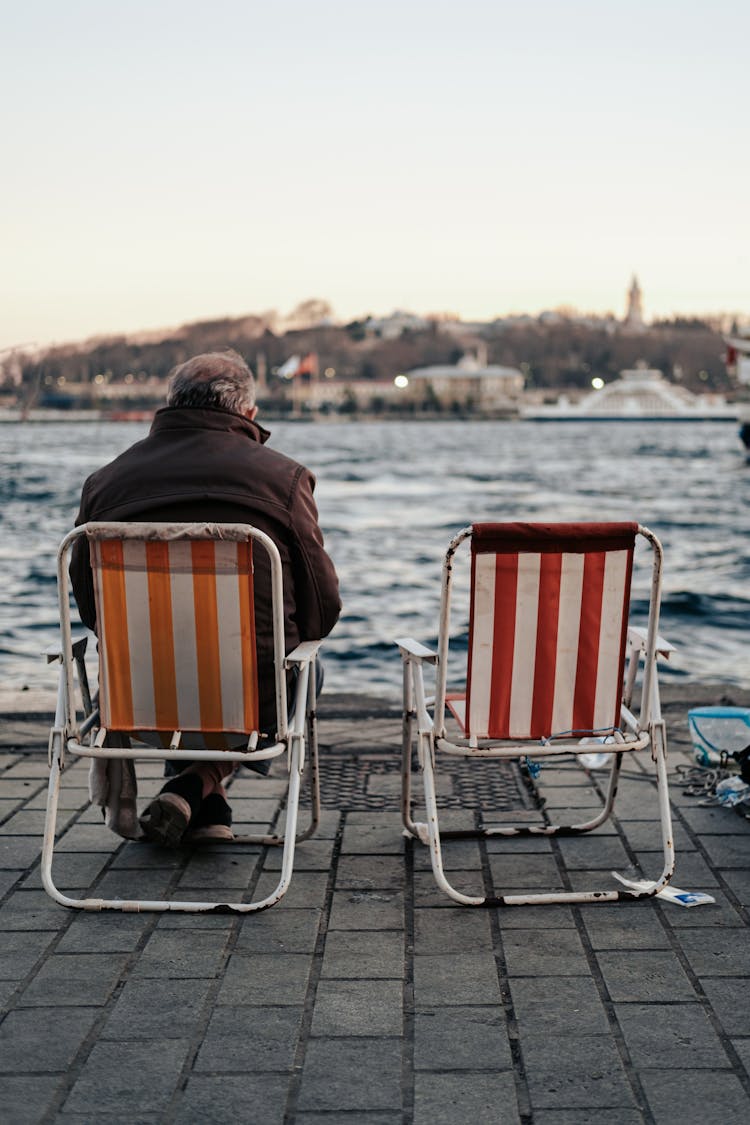 Man Sitting At The Edge Of The Water In A City