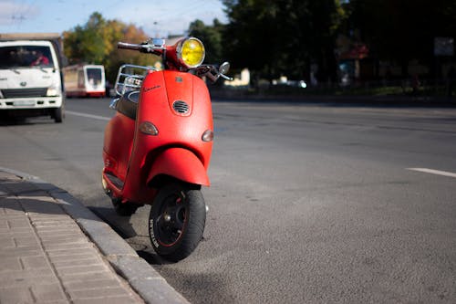 A Red Scooter Parked on the Side of the Road 